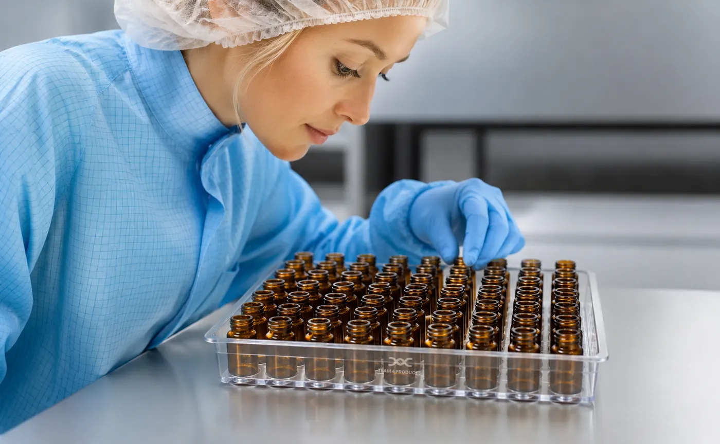 Technician inspecting a Team 4 tray of amber vials